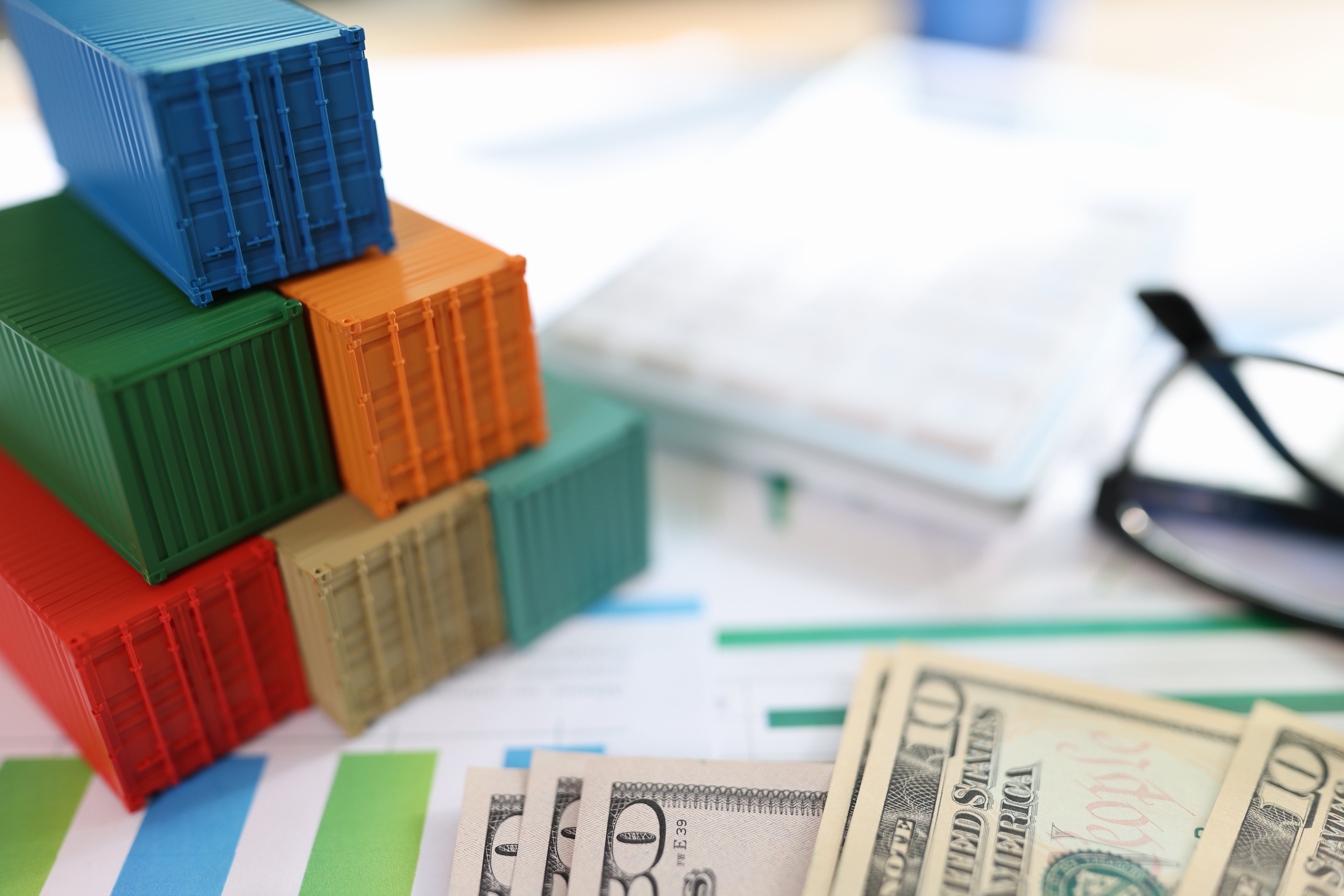 cargo-containers-with-dollar-banknotes-glasses-financial-document-shallow-depth-field