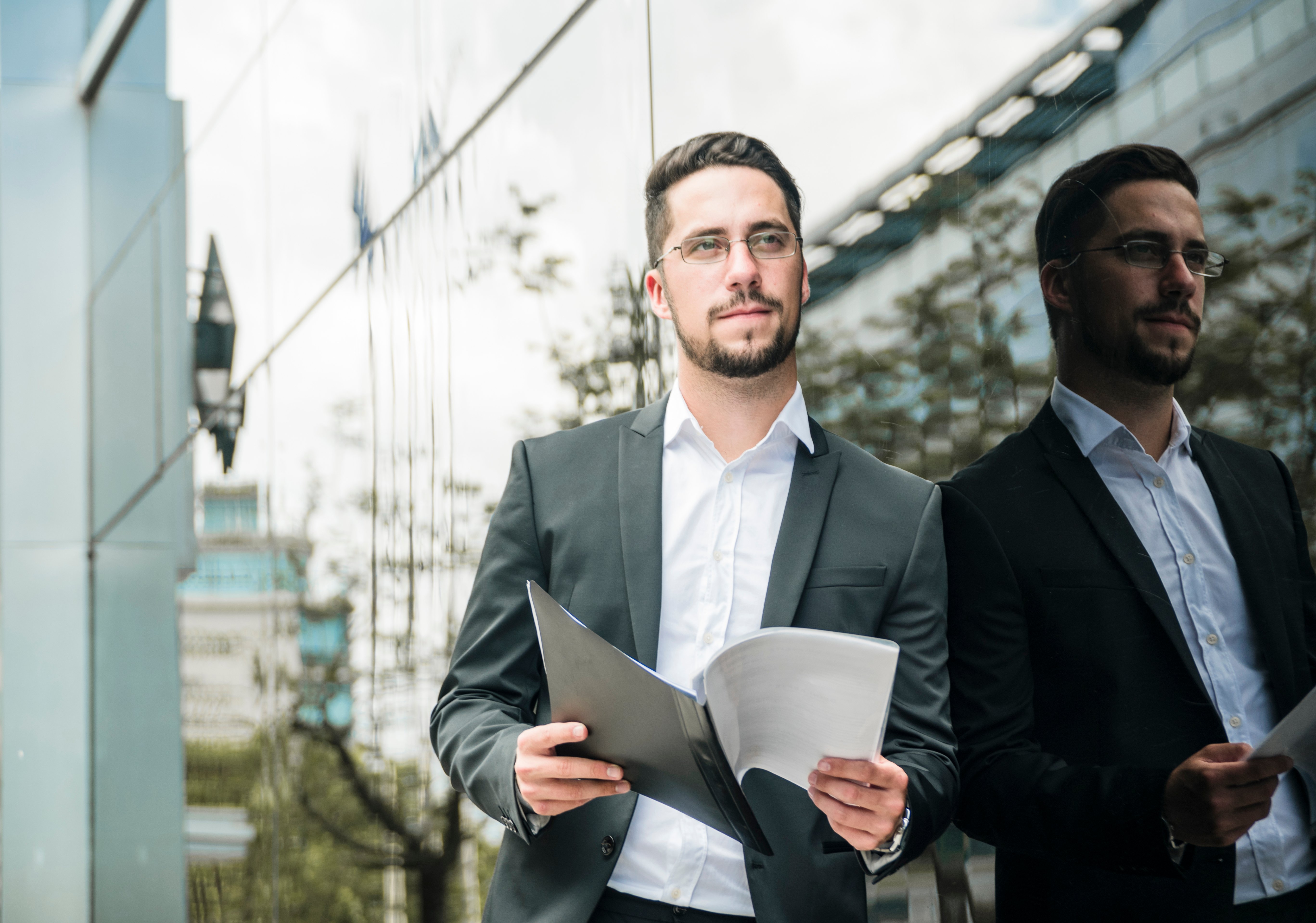 handsome-young-businessman-holding-folder-hand-looking-away